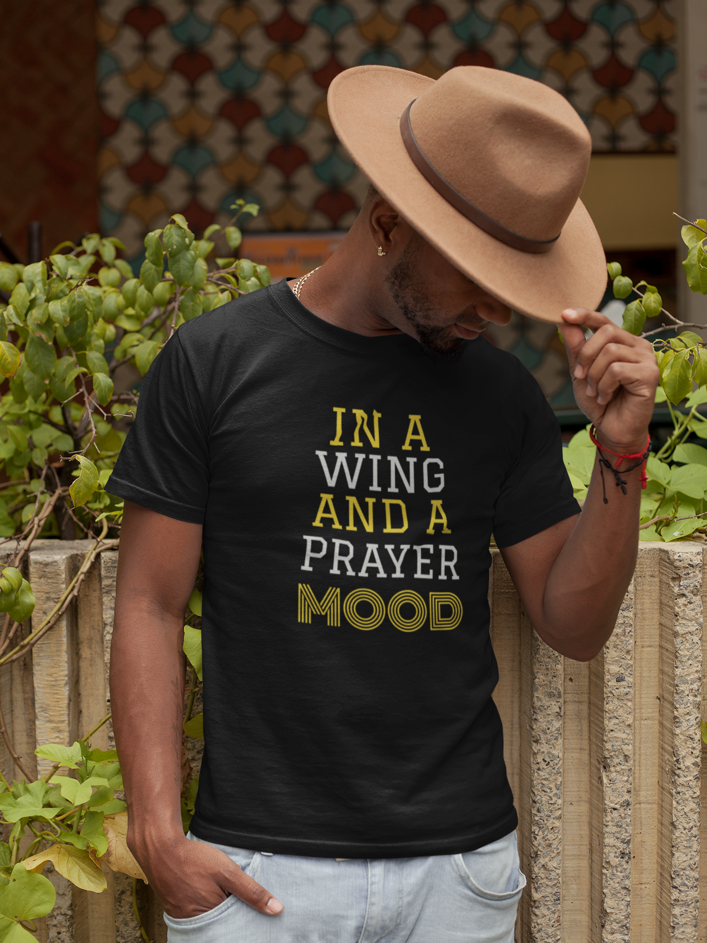 man holding head down with hat with black tee with gold and white letters and reads-In a Wing and a Prayer Mood Inspirational tshirt, Christian Prayer tee, mental health awareness t-shirt, Nurse week tee, gift for Christian, gift for pastor, worship leader gift choir gift , family tee,*** See Matching Mug, Mousepad, and Notebook, many colors available